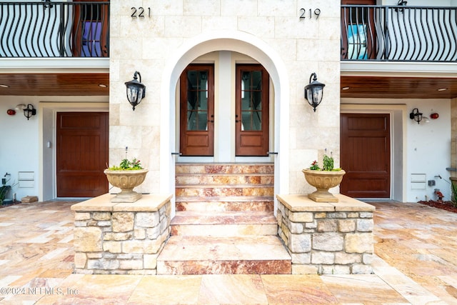 219 11th Ave S, Jacksonville Beach, FL 32250 - view of exterior entry featuring a balcony, stone siding, and french doors