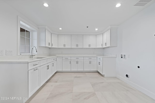 kitchen with sink, light stone countertops, and white cabinetry