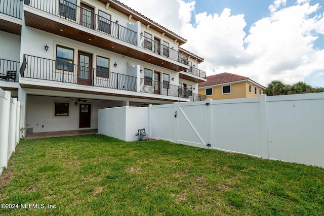 exterior space with a balcony, a patio area, a lawn, and ceiling fan