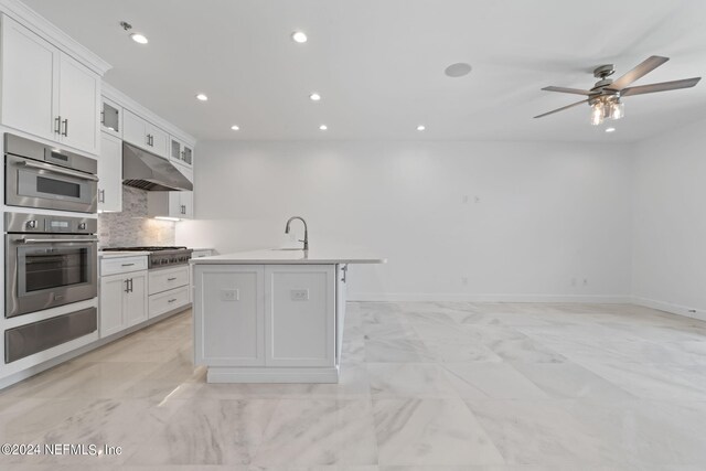 kitchen featuring white cabinetry, sink, stainless steel gas cooktop, ceiling fan, and a center island with sink