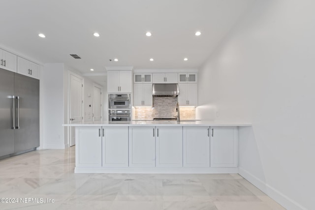 kitchen featuring stainless steel appliances, kitchen peninsula, white cabinetry, and decorative backsplash