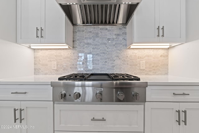 kitchen featuring stainless steel gas stovetop, wall chimney exhaust hood, white cabinetry, and tasteful backsplash