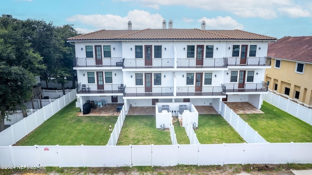 rear view of property featuring a balcony and a lawn