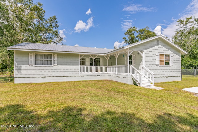 rear view of house featuring covered porch and a yard