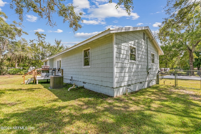 view of home's exterior with a lawn, central AC unit, and a deck