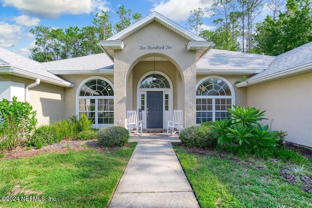 view of exterior entry featuring a lawn