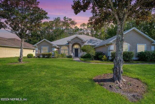 ranch-style house featuring a lawn and a garage