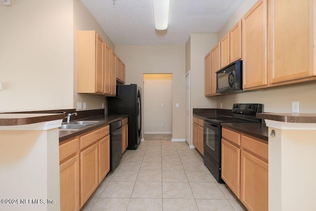 kitchen featuring dark countertops, a sink, black appliances, and light tile patterned floors