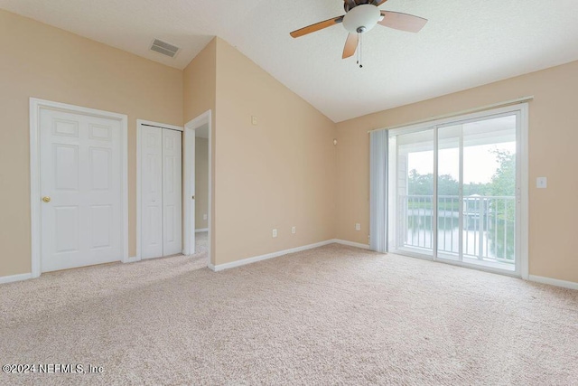 unfurnished bedroom with access to exterior, light colored carpet, visible vents, and vaulted ceiling