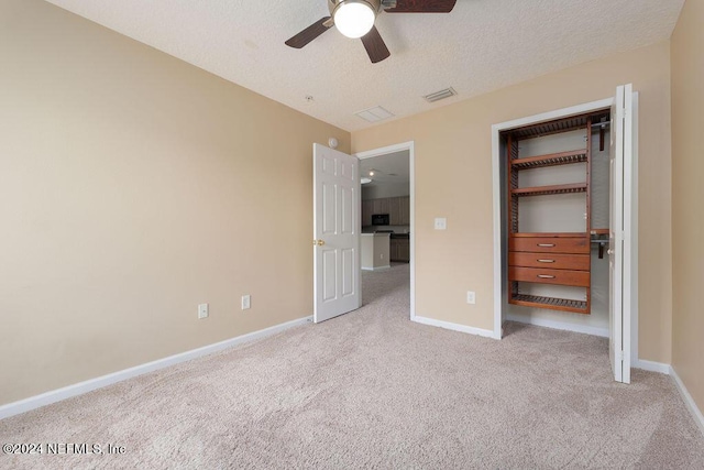 unfurnished bedroom featuring a closet, visible vents, light carpet, a textured ceiling, and baseboards