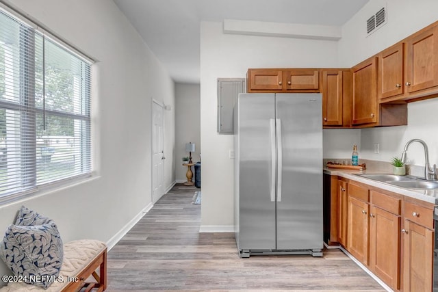 kitchen featuring light wood-type flooring, stainless steel refrigerator, and sink