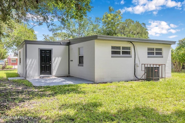 back of property with central AC unit, a yard, and a patio area