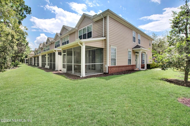 rear view of property featuring a sunroom and a lawn