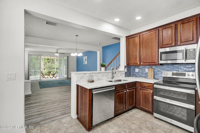 kitchen featuring sink, decorative light fixtures, light hardwood / wood-style flooring, tasteful backsplash, and stainless steel appliances