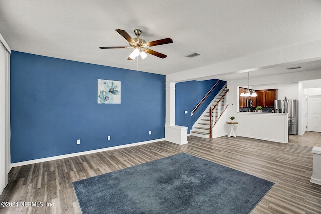 interior space with a textured ceiling, ceiling fan with notable chandelier, and hardwood / wood-style flooring