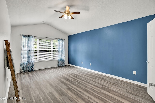 unfurnished room with ceiling fan, hardwood / wood-style flooring, a textured ceiling, and lofted ceiling