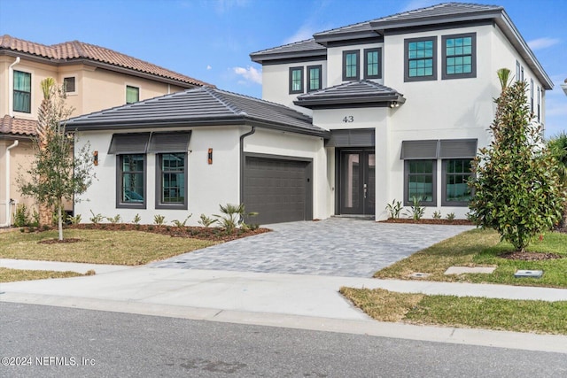 view of front facade with a garage, a front yard, decorative driveway, and stucco siding