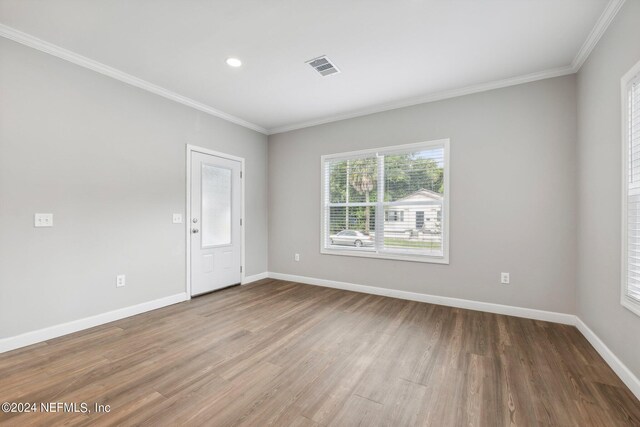 empty room featuring baseboards, ornamental molding, and visible vents