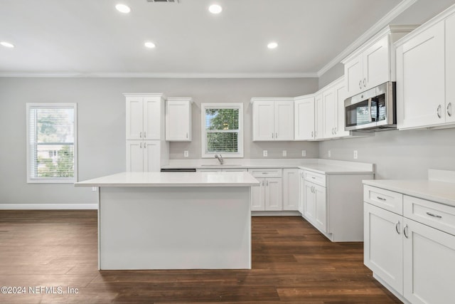 kitchen with dark wood finished floors, a healthy amount of sunlight, crown molding, and stainless steel microwave