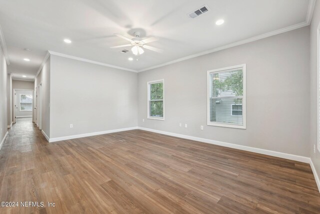 empty room with visible vents, baseboards, ceiling fan, ornamental molding, and wood finished floors