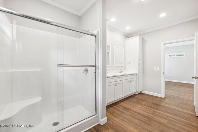 bathroom featuring ornamental molding, wood finished floors, and a shower stall