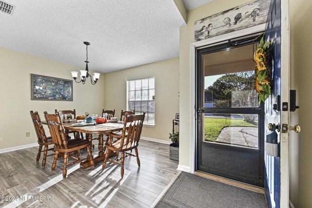 dining space with a notable chandelier, a textured ceiling, and wood-type flooring