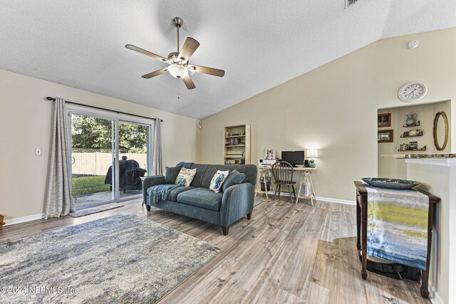 living room with light hardwood / wood-style floors, vaulted ceiling, ceiling fan, and a textured ceiling