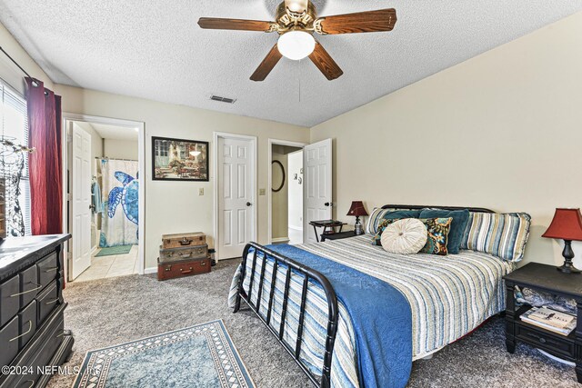 bedroom featuring light colored carpet, a textured ceiling, ensuite bath, and ceiling fan