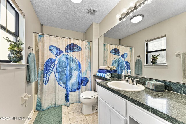 bathroom with vanity, tile patterned flooring, a textured ceiling, curtained shower, and toilet