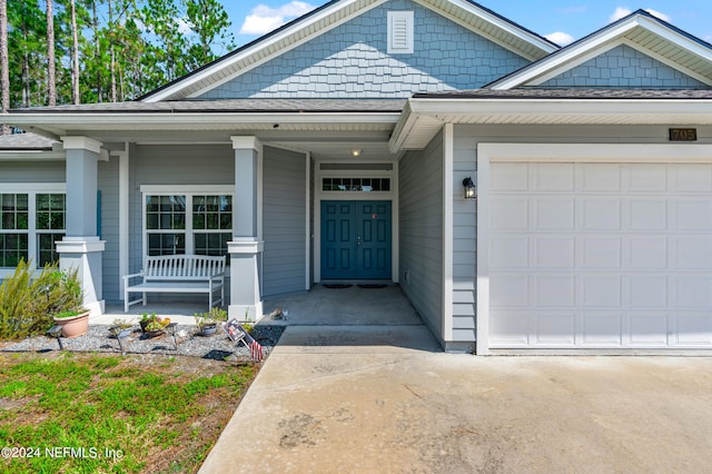 view of exterior entry featuring a garage and a porch