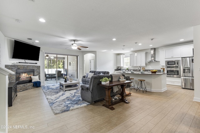 living room with light wood-type flooring, a healthy amount of sunlight, a fireplace, and recessed lighting