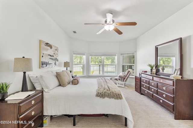 bedroom featuring a ceiling fan, multiple windows, visible vents, and light colored carpet