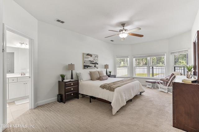 bedroom featuring light colored carpet, visible vents, connected bathroom, a sink, and baseboards