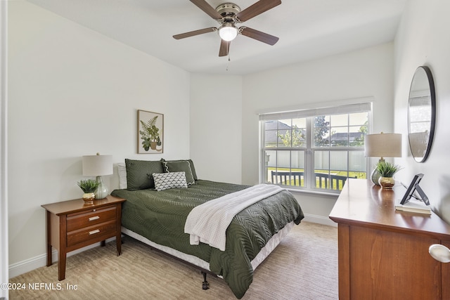 bedroom with a ceiling fan, light colored carpet, and baseboards