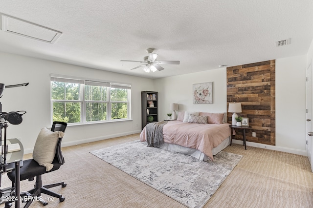 bedroom featuring ceiling fan, a textured ceiling, wooden walls, light carpet, and visible vents