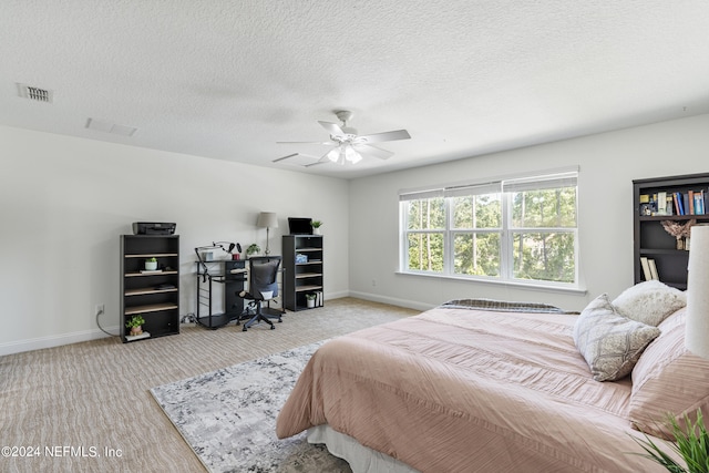 bedroom featuring light carpet, baseboards, visible vents, a ceiling fan, and a textured ceiling