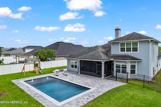 rear view of house with a playground, a patio, a lawn, a sunroom, and a fenced backyard