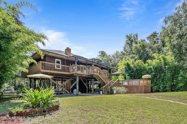 rear view of house featuring a chimney, stairway, a deck, and a lawn