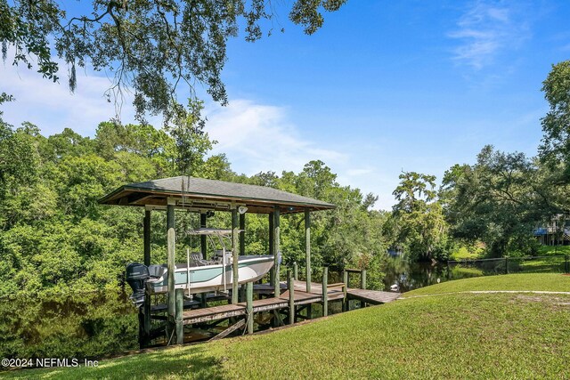 view of dock with a lawn and a water view