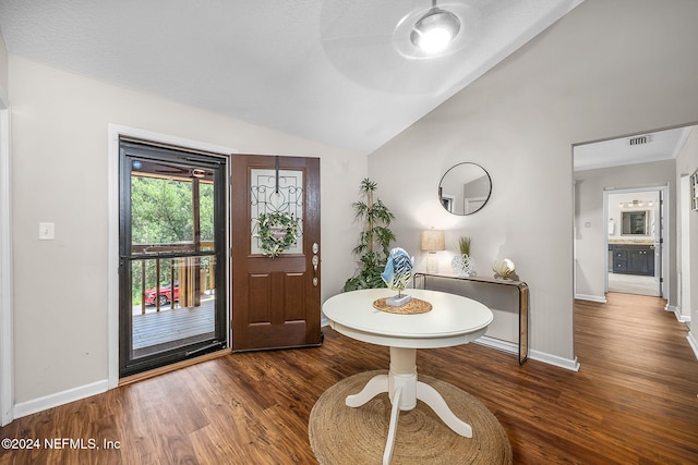 foyer with lofted ceiling, baseboards, visible vents, and wood finished floors