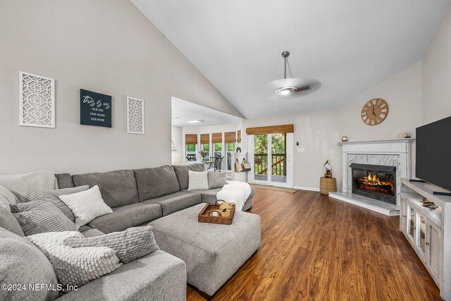 living room with ceiling fan, high vaulted ceiling, a high end fireplace, and dark hardwood / wood-style flooring