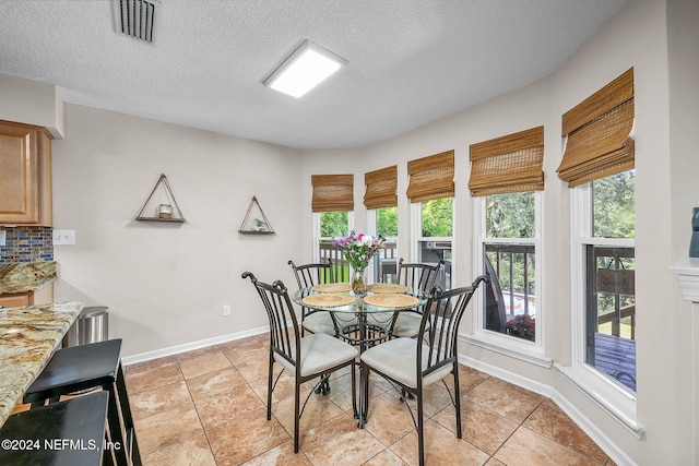 dining space featuring light tile patterned floors, baseboards, visible vents, and a textured ceiling