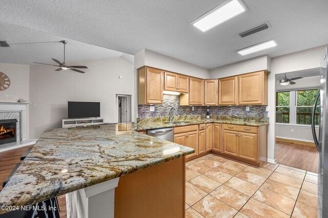 kitchen with ceiling fan, light hardwood / wood-style floors, light stone countertops, and a premium fireplace