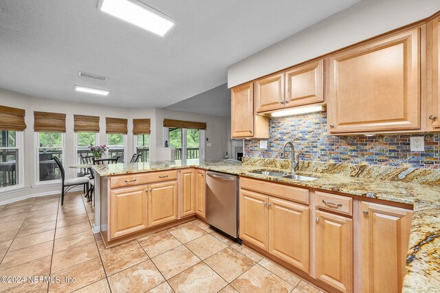 kitchen with sink, light stone countertops, stainless steel dishwasher, light tile patterned floors, and kitchen peninsula