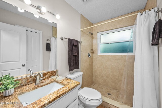 bathroom with a shower with shower curtain, toilet, a textured ceiling, and vanity