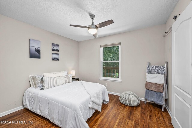 bedroom featuring ceiling fan, a textured ceiling, and dark hardwood / wood-style floors