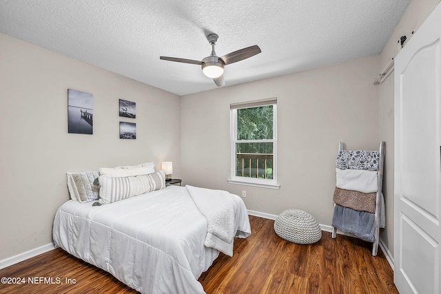 bedroom featuring a ceiling fan, a textured ceiling, baseboards, and wood finished floors