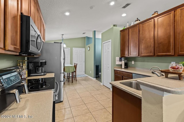 kitchen featuring sink, vaulted ceiling, light tile patterned floors, and stove