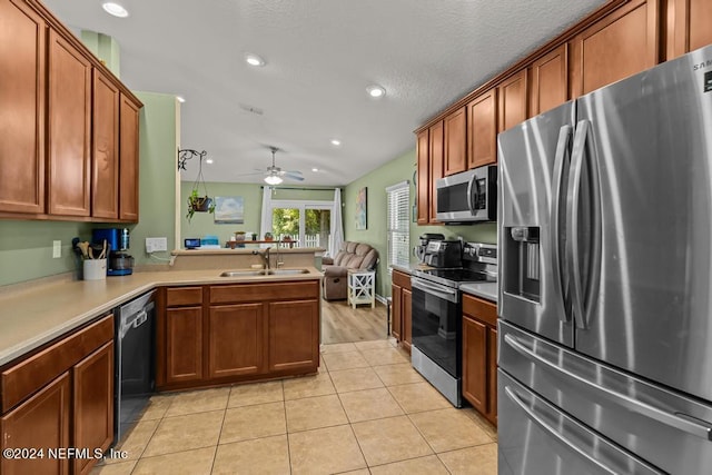 kitchen featuring sink, light wood-type flooring, ceiling fan, stainless steel appliances, and kitchen peninsula