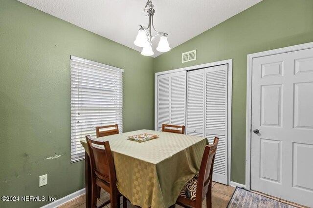 tiled dining space with vaulted ceiling and an inviting chandelier